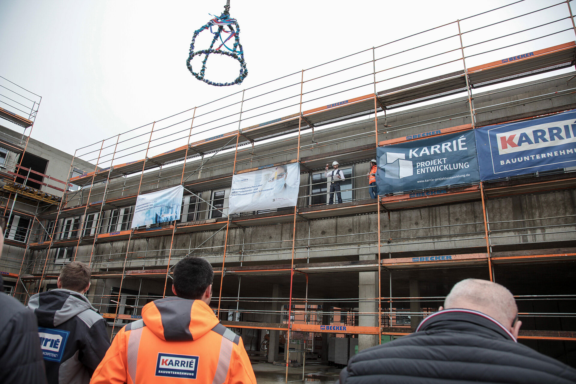 Richtfest des Neubaus – Geschichte der MVZ GANZIMMUN GmbH Richtfest auf der Baustelle mit Bauarbeitern und aufgehängtem Richtkranz – ein bedeutender Meilenstein in der Geschichte der MVZ GANZIMMUN GmbH.